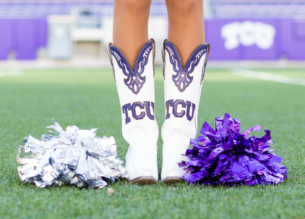 A TCU Showgirl’s legs wearing her boots posed to show off her custom white and purple TCU boots.